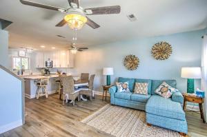 a living room with a blue couch and a kitchen at Coastal Oasis with Decks Walk to Holden Beach! in Holden Beach