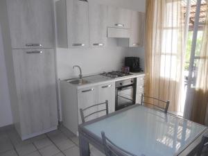 a kitchen with white cabinets and a table with chairs at Villa Mercadante in Capo dʼOrlando