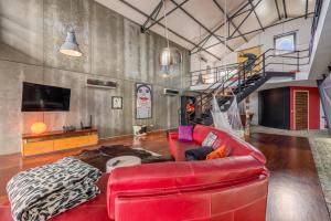 sala de estar con sofá de cuero rojo y escalera en The Loft - a birdwatchers paradise, en Fuseta