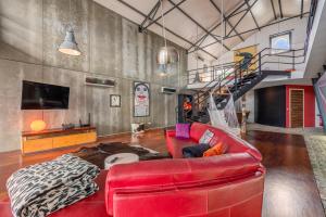 a living room with a red leather couch and a staircase at The Loft - a birdwatchers paradise in Fuzeta