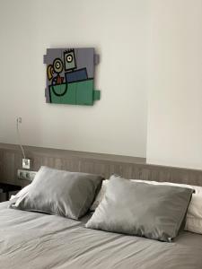 1 cama con 2 almohadas y una pintura en la pared en Apartaments El Cine, en Roses