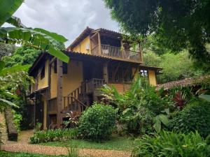 a yellow house with a balcony in a garden at A Arte de Bem Viver in Tiradentes