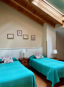 2 Betten in einem Schlafzimmer mit blauer Bettwäsche in der Unterkunft El Hayuco de Montejo in Montejo de la Sierra
