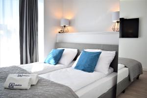 Schlafzimmer mit einem Bett mit blauen und weißen Kissen in der Unterkunft Apartos Apartamenty Grano Residence in Danzig