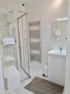 baño blanco con ducha y lavamanos en 12 Rue des Ecoles en Saint-Émilion
