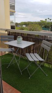 ein weißer Tisch und zwei Stühle auf einem Balkon in der Unterkunft JOLI STUDIO 50M DE LA MER in Valras-Plage