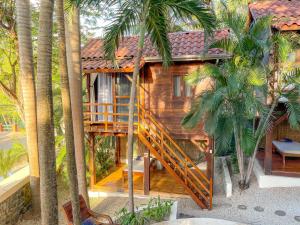 a house with a staircase leading up to it with palm trees at The Beach Bungalows - Yoga and Surf House - Adults Only in Tamarindo