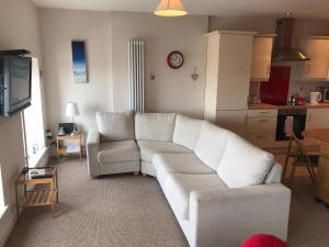 a living room with a white couch and a kitchen at West Strand View in Portrush