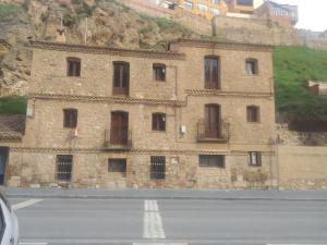 a building on the side of a mountain next to a road at Apartamento Bajo Los Arcos in Teruel