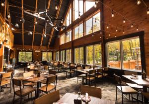 a dining room with tables and chairs and windows at Camelback Resort in Tannersville