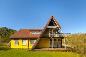 una casa amarilla con techo de gambrel en Nostalgija Pervalkoje, en Neringa