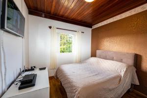 1 dormitorio con cama, escritorio y ventana en Ap Casal Localização e Segurança, en Campos do Jordão