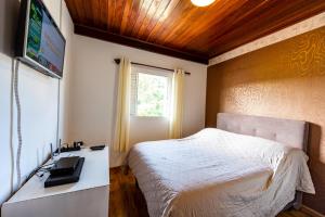 a bedroom with a bed and a desk and a television at Ap Casal Localização e Segurança in Campos do Jordão