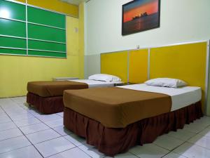 two beds in a room with green and yellow walls at Hotel Nirwana Ternate RedPartner in Ternate
