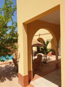 an outdoor patio with chairs and an umbrella at Magnifique Villa Riad avec piscine proche plage in Saly Portudal