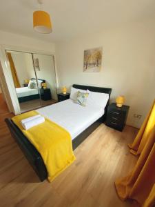 a bedroom with a large bed with a yellow blanket at The OVO Hydro Penthouse With Free Parking in Glasgow