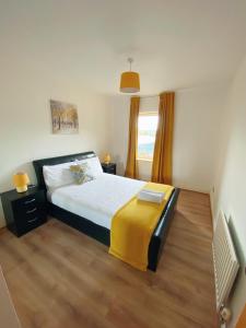 - une chambre avec un lit et une couverture jaune dans l'établissement The OVO Hydro Penthouse With Free Parking, à Glasgow