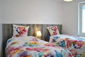 a bedroom with two beds with floral sheets and a lamp at L'HIRONDELLE in Saint-Laurent-de-Mure