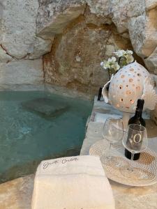 una bottiglia di vino e un bicchiere accanto a una piscina d'acqua di Grotta Carlotta a Ostuni