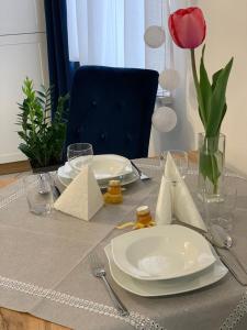 a table with plates and utensils and a red rose at Apartament Fordon przy Onkologii in Bydgoszcz