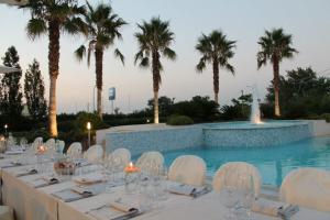 uma mesa longa com cadeiras brancas e uma piscina em Hotel Altamira em Orsogna
