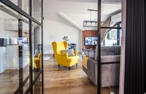 a living room with a yellow chair and a couch at Apartamenty W37 in Nowy Targ