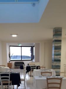 una sala da pranzo con tavoli, sedie e una finestra di Hotel Il Riccio a Porto Cesareo