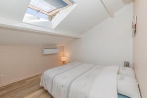 a white bedroom with a bed and a skylight at Loc'Apparts Montpellier in Montpellier
