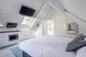 a white bedroom with a large bed and a tv at Slapen bij Jansz in Kamperland