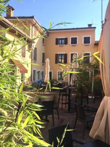 eine Terrasse mit Tischen und Stühlen und ein Gebäude in der Unterkunft Hotel e Locanda La Bastia in Valeggio sul Mincio