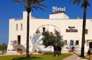 a white building with palm trees in front of it at Relais Sant'Eligio in Ostuni