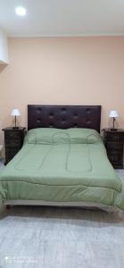 Un dormitorio con una cama verde con dos mesitas de noche. en Look Departamentos, en Carhué