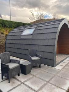 a roofed patio with two chairs and a table at Mallaig Glamping Pods in Mallaig