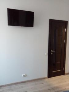 uma televisão de ecrã plano numa parede branca com uma porta em Апартаменты в центре города em Chernivtsi