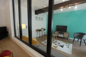 a living room with a large window and a room with a television at Appartement centre de Valenciennes entièrement équipé 64m2 in Valenciennes