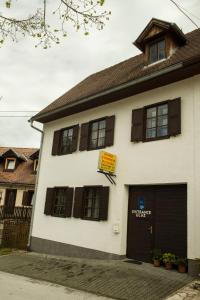 un bâtiment blanc avec des fenêtres marron et un garage dans l'établissement Rooms Roza, à Slunj