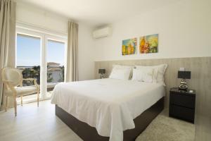 a bedroom with a white bed and a large window at Villa Bellevue in Albufeira