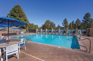 a large swimming pool with chairs and an umbrella at Club Wyndham Flagstaff in Flagstaff