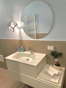 Appartamento Azzurro في فيرونا: حمام مع حوض ومرآة مستديرة