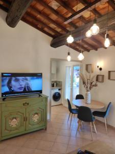 ein Wohnzimmer mit einem TV und einem Tisch mit Stühlen in der Unterkunft La Ramade de Saint-Tropez in Saint-Tropez