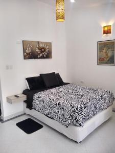 Dormitorio blanco con cama blanca y negra en La Habitación Perfecta, en Barranquilla