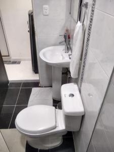 a white bathroom with a toilet and a sink at La Habitación Perfecta in Barranquilla