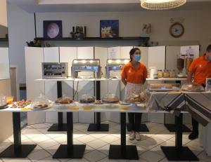 une femme portant un masque debout dans une cuisine avec une table de nourriture dans l'établissement El Cid Campeador, à Rimini