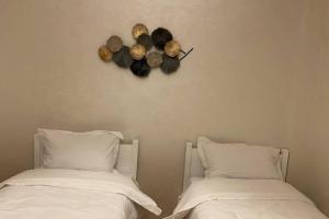 two beds with white sheets and a clock on the wall at Du Haut Standing au coeur du Parc et Plage à 180 m in Mohammedia +30 photos