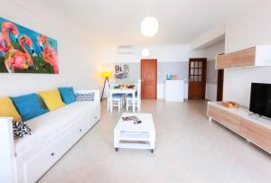 een woonkamer met een witte bank en een tafel bij ALTIUM Cabanas in Cabanas de Tavira