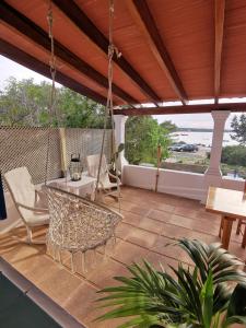 eine Veranda mit einer Schaukel, einem Tisch und Stühlen in der Unterkunft Casa frente al lago in La Savina