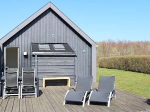 12 person holiday home in Hadsund في Nørre Hurup: مجموعة من الكراسي على سطح مع مبنى