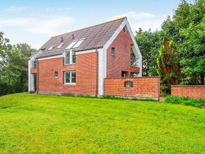 une maison en briques rouges avec une grande pelouse dans l'établissement 6 person holiday home in Fars, à Hvalpsund