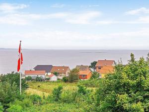 a house on a hill with a flag and the ocean at 6 person holiday home in Fars in Hvalpsund