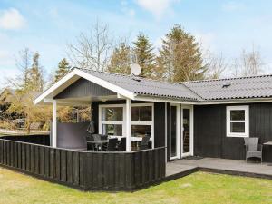 una casa negra con una terraza con sillas en Holiday home Hadsund XX en Nørre Hurup